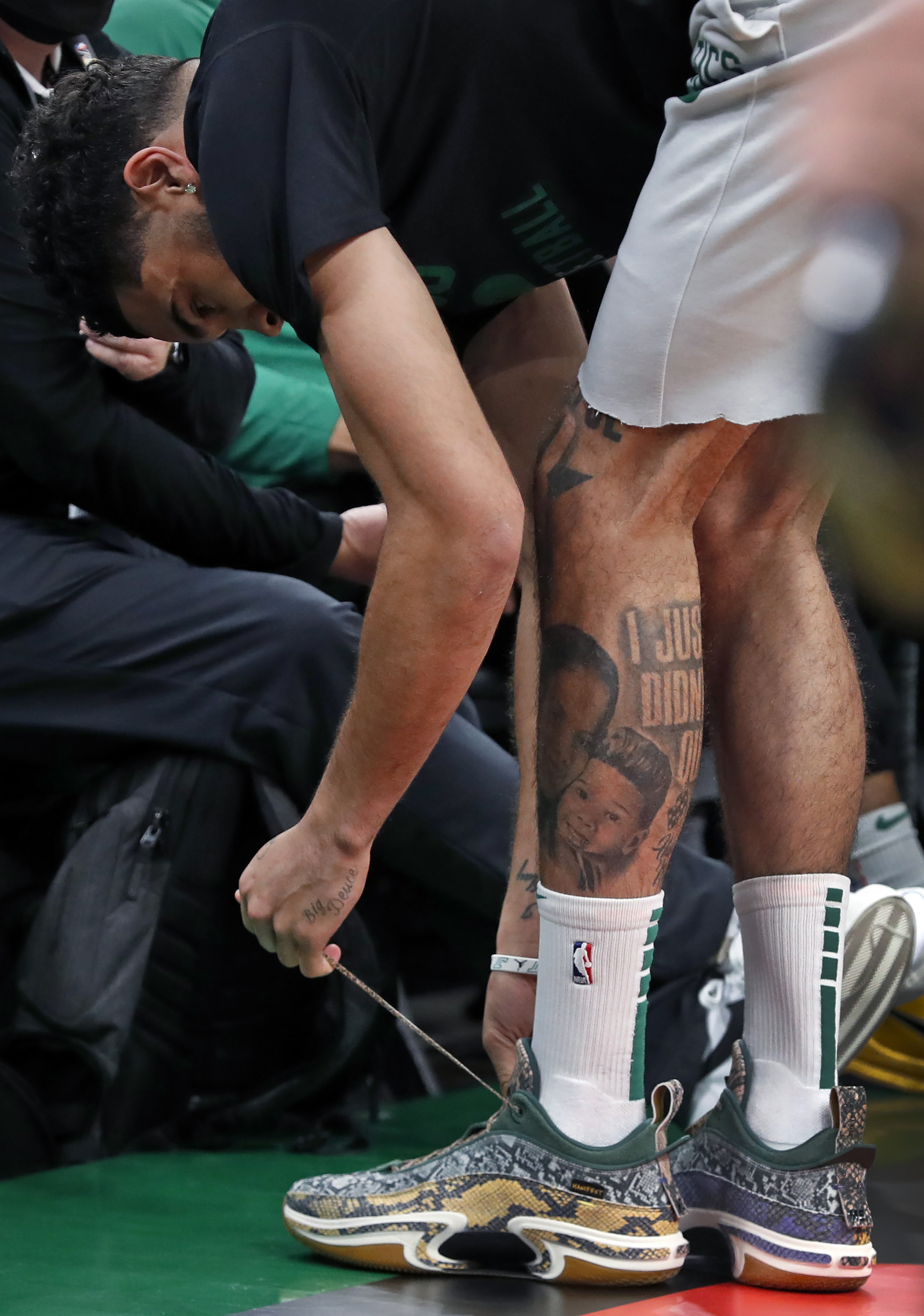 Tatum ties his laces before an NBA game